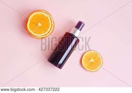 Unbranded Brown Cosmetic Spray Bottle And Orange Slices On Pink Background. Natural Organic Spa Cosm