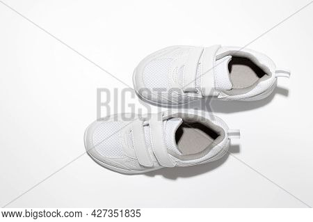 Flat Lay White Childrens Running Shoes Imitating Walking With Hard Shadows Isolated On A White Backg