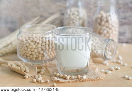 Closed Up Soybean Milk In Glass Over Blur Soybean Seed And Milk In Glass Bottle And Jug Background, 