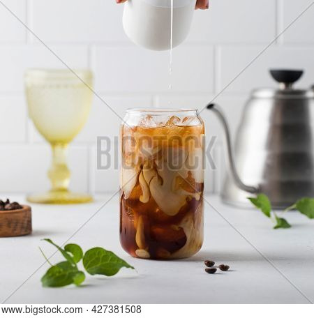 Cream Is Poured Into Cold Black Coffee With Ice Cubes. Coldbrew. Summer Drinks.