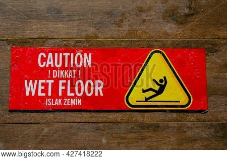 Red Warning Sticker For Wet Floor On Brown Tiled Floor. The Inscription On Red Information Sticky La