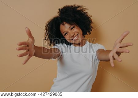 Happy Friendly African American Woman Dressed In White Shirt Offering Hugs And Looking At Camera Wit
