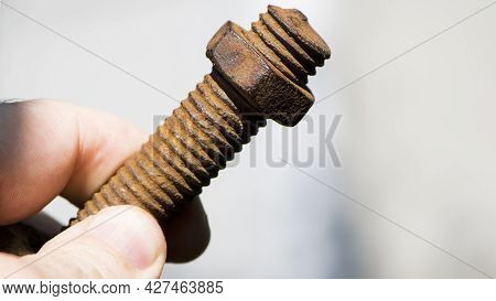 Old Rusty Bolt, Iron Rod With Screw Threads, In Hand. Rusted Mechanical Components. Holding Threaded