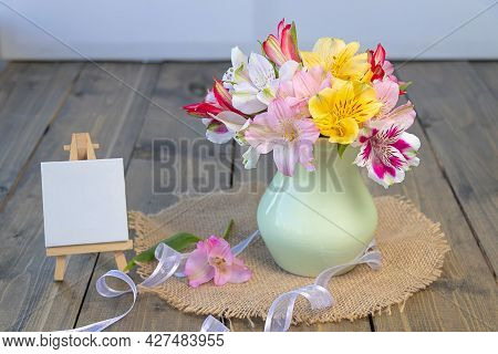 Multi-colored Flowers In A Clay Vase, Empty Molbert With Copy Space On A Wooden Background. Multicol