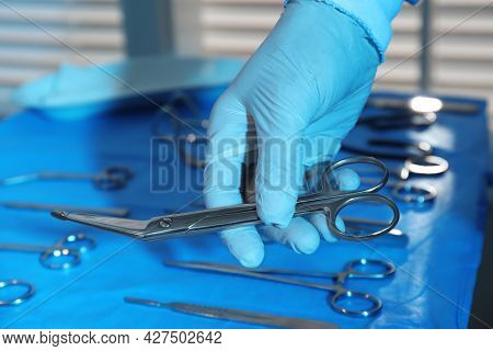 Doctor Taking Pott's Scissors From Table With Different Surgical Instruments Indoors, Closeup