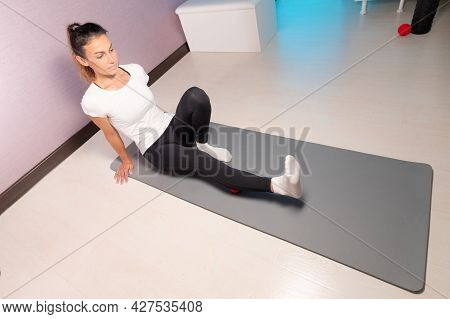 Sporty Slim Caucasian Woman Doing Self Massage On Fitness Mat With Massage Ball Indoors. Self-isolat