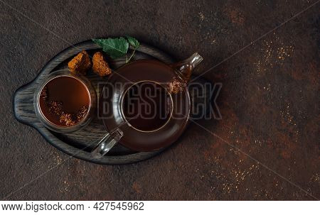 Chaga Tea Drink. Chaga Mushroom Infusion In Teapot And Cup On A Dark Brown Background. Organic Drink