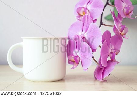 Mock-up Of One White Mug On Table With Lilac Orchid Flowers Decor. Template, Layout For Your Design,