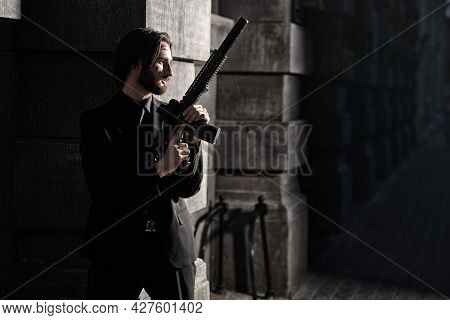Wounded special agent with an automatic gun on a mission on the street of a night city. 