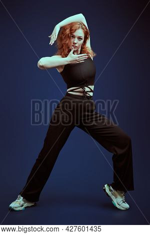 Professional modern style dancer girl dancing at studio on a dark blue background. Modern dance style. 
