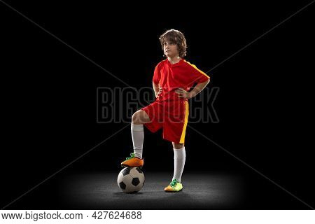 Portrait Of Little Boy, Football Soccer Player Posing With Football Ball Isolated On Dark Studio Bac