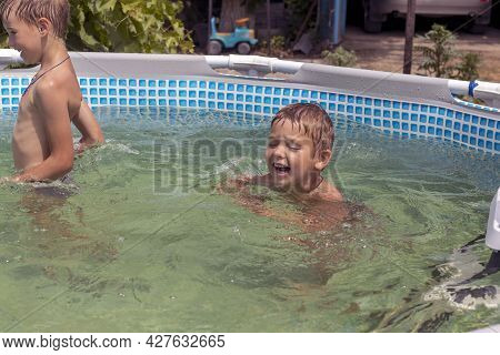 Boy Splashing Happily In The Water On A Sunny Day.
Boy Bathes In A Frame Pool
