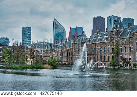 View of the Binnenhof House of Parliament and the Hofvijver lake with downtown skyscrapers in background. The Hague, Netherlands