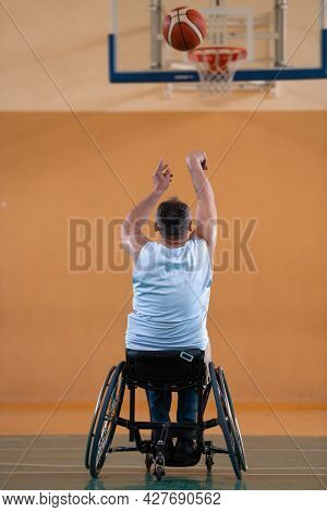 a war  in a wheelchair trains with a ball at a basketball club in training with professional sports equipment for the disabled. the concept of sport for people with disabilities