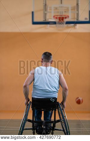 a war  in a wheelchair trains with a ball at a basketball club in training with professional sports equipment for the disabled. the concept of sport for people with disabilities