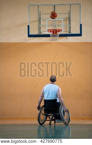 a war  in a wheelchair trains with a ball at a basketball club in training with professional sports equipment for the disabled. the concept of sport for people with disabilities
