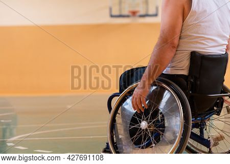 Close up photo of wheelchairs and handicapped war veterans playing basketball on the court