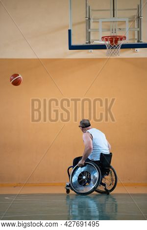 a war  in a wheelchair trains with a ball at a basketball club in training with professional sports equipment for the disabled. the concept of sport for people with disabilities