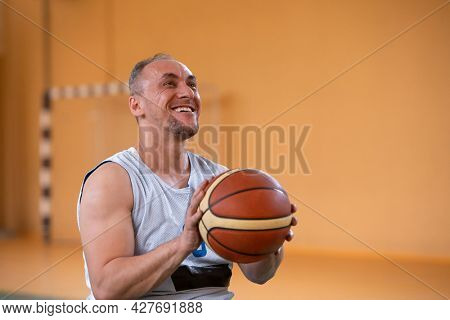 a photo of a war veteran playing basketball with a team in a modern sports arena. The concept of sport for people with disabilities
