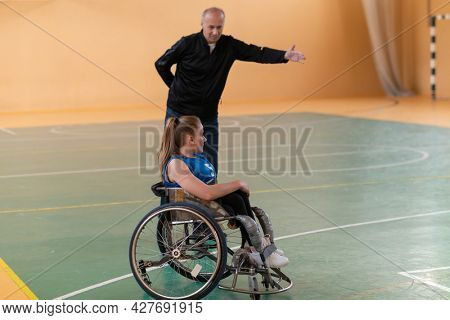 a sports basketball coach explains to a disabled woman in a wheelchair which position to play during a game