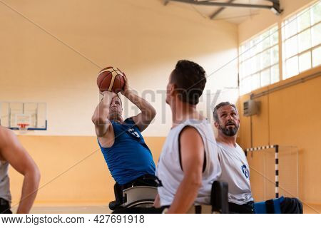 handicapped war veterans in wheelchairs with professional equipment play basketball match in the hall.the concept of sports with disabilities