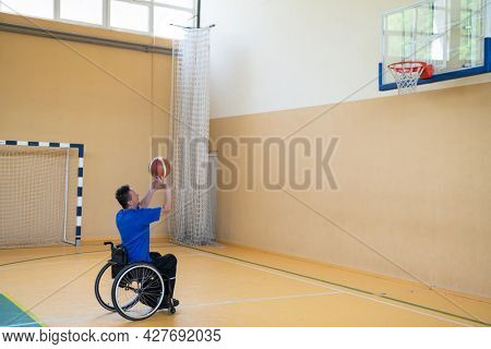 a war  in a wheelchair trains with a ball at a basketball club in training with professional sports equipment for the disabled. the concept of sport for people with disabilities