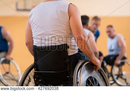 Close up photo of wheelchairs and handicapped war veterans playing basketball on the court