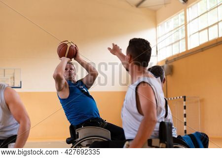handicapped war veterans in wheelchairs with professional equipment play basketball match in the hall.the concept of sports with disabilities