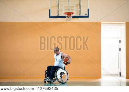 a war  in a wheelchair trains with a ball at a basketball club in training with professional sports equipment for the disabled. the concept of sport for people with disabilities