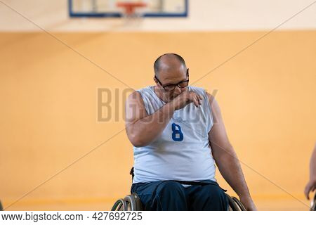a photo of a war veteran playing basketball with a team in a modern sports arena. The concept of sport for people with disabilities