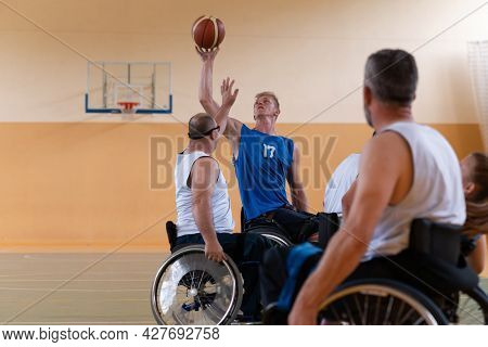 handicapped war veterans in wheelchairs with professional equipment play basketball match in the hall.the concept of sports with disabilities
