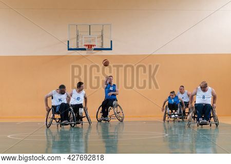 handicapped war veterans in wheelchairs with professional equipment play basketball match in the hall.the concept of sports with disabilities