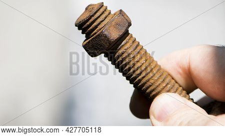 Old Rusty Bolt, Iron Rod With Screw Threads, In Hand. Rusted Mechanical Components. Holding Threaded