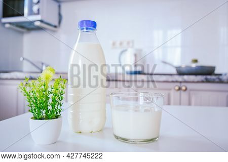 A Bottle Of Milk And A Full Glass Cup On The Kitchen Table In The Background Of The Cozy Light Kitch