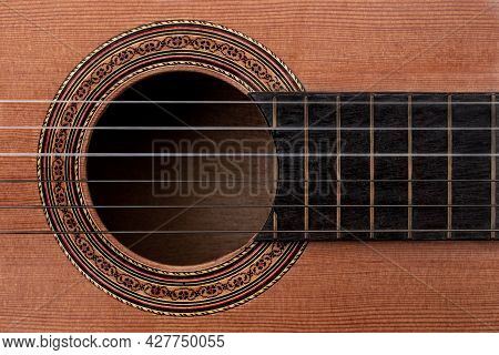 Close-up Of Old Acoustic Guitar Showing Detail Of Decorative Rosette Decal Around Soundhole, Strings