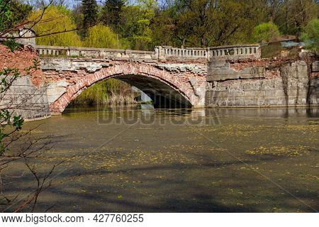 Old Arched Brick Bridge Across A Pond In Sharovka Palace Park In In Kharkov Region, Ukraine