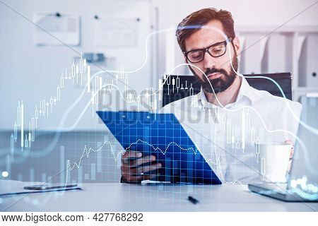 Handsome Beard Businessman Trader In Glasses Is Sitting At Workplace And Working With Documents To C