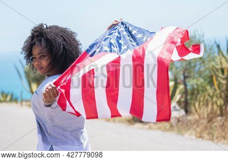 Afro American Girl Waving An American Flag On A Road