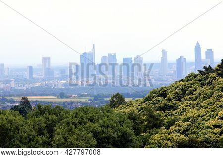 The Skyline Of Frankfurt, Hessen, Germany Behind A Small Forest