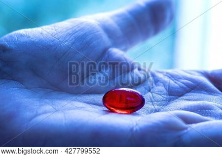 Bright Red Capsule With Medicine In Palm Of Your Hand.