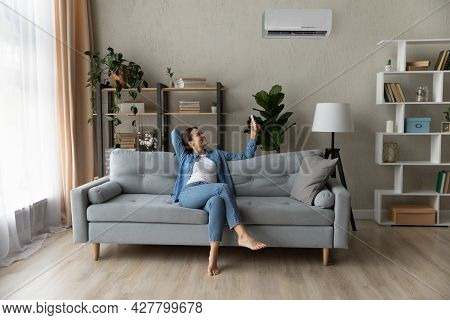 Woman Relax On Couch Holding Remote Controller Turns On Airconditioner