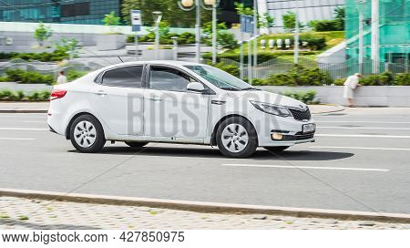 Moscow, Russia - July 2021: White Kia Rio Sedan On Asphalt Road In Summer Day In Blurred Urban Lands