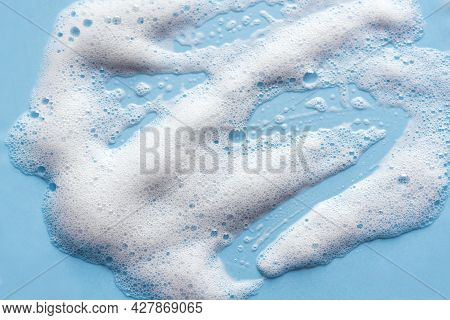 Face Cleansing Mousse Sample. White Cleanser Foam Bubbles On Blue Background. Soap, Shower Gel, Sham