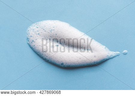 Face Cleansing Mousse Sample. White Cleanser Foam Bubbles On Blue Background. Soap, Shower Gel, Sham