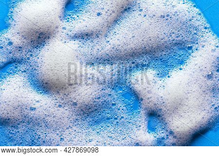 Face Cleansing Mousse Sample. White Cleanser Foam Bubbles On Blue Background. Soap, Shower Gel, Sham