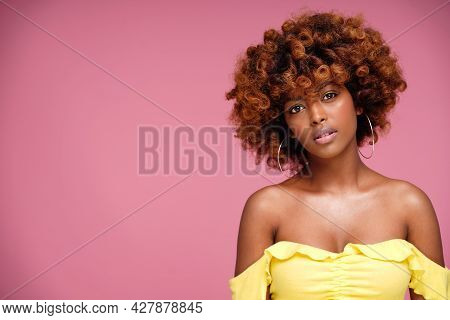 Beauty Portrait Of Afro Woman With Glamour Summer Makeup And Curly Hairstyle. Pink Pastel Background