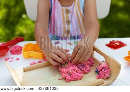 Hands Of Little Girl Playing With Kinetic Sand Close-up. Leisure Activity Outdoors In Summer Day.