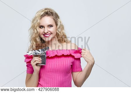 Smiling Caucasian Blond Girl With Unwrapped Bar Of Chocolate Looking Upwards On White. Horizontal Im