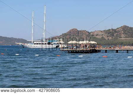 Hisaronu, Turkey​ -​ July 2021: People Sunbathing On A Beach On Aegean Coast. View To The Yachts And