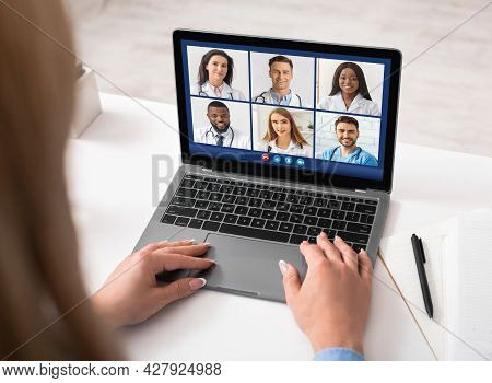 Lady Doctor At Laptop Video Calling Diverse Colleagues Indoors, Back-view